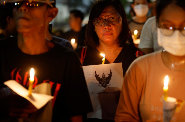 Netiporn's friends and supporters at a memorial for her. The are holding candles.