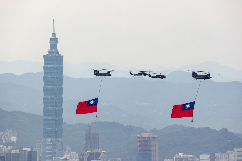 Helicopters carrying Taiwan's national flags in the sky above Taipei. Taipei 101 is behind them. 