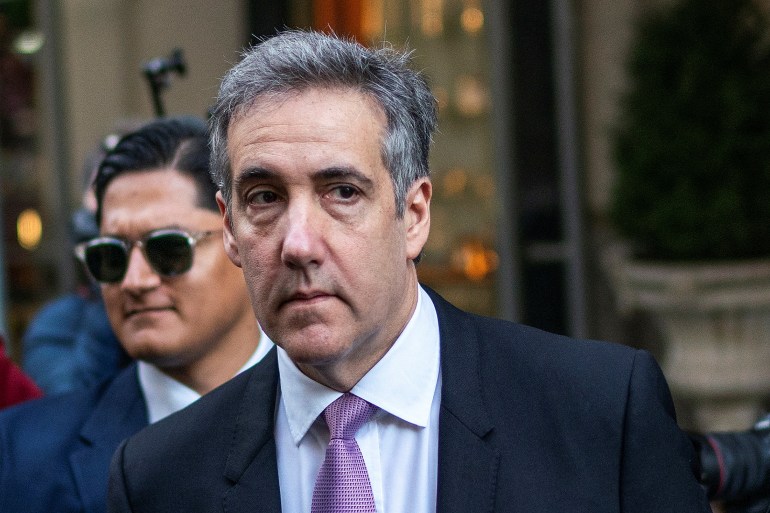 Michael Cohen, wearing a suit and pink tie, walks outside his apartment building in New York.