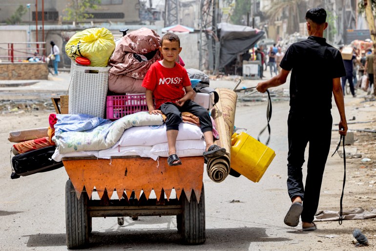 A boy looks on as he sits atop cushions and mattresses loaded in the back of an animal-drawn cart led by a man as they evacuate from Sheikh Zayed in the northern Gaza Strip