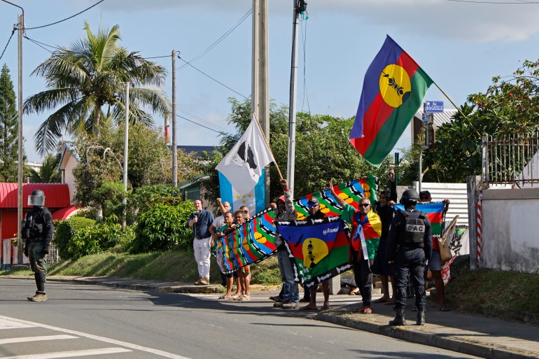 people hold brightly coloured flags on a tropical street