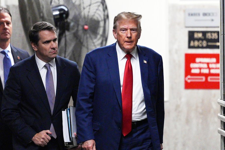 Donald Trump, wearing a blue suit and red tie, walks into the Manhattan criminal courthouse.