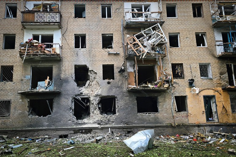 An apartment block damaged in a Russian attack on Kherson. Windows are missing and balconies mangled, There is major damage to the facade.