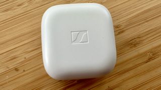 Gray Sennheiser Accentum True Wireless earbuds case on a wooden table