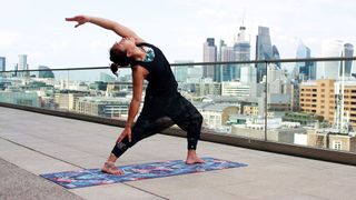 Woman doing yoga on Form Pro Travel yoga Mat on a rooftop with London skyline in the background