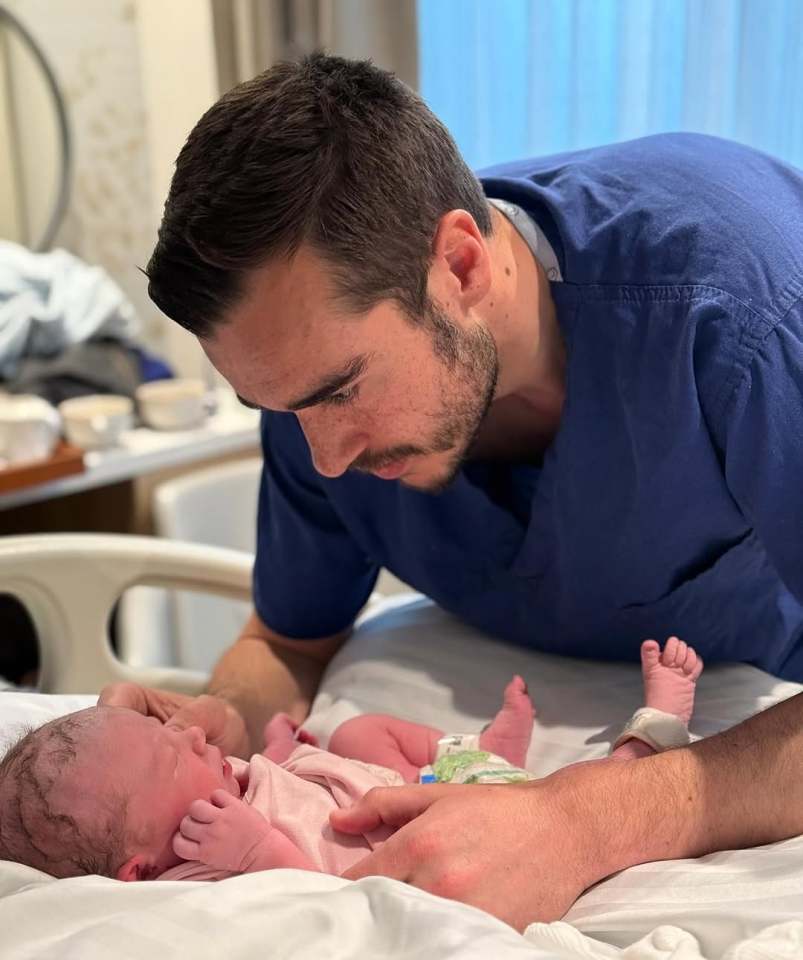 A father looking at his newborn baby daughter.