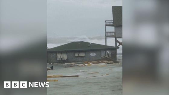 Moment houses on stilts topple into the sea